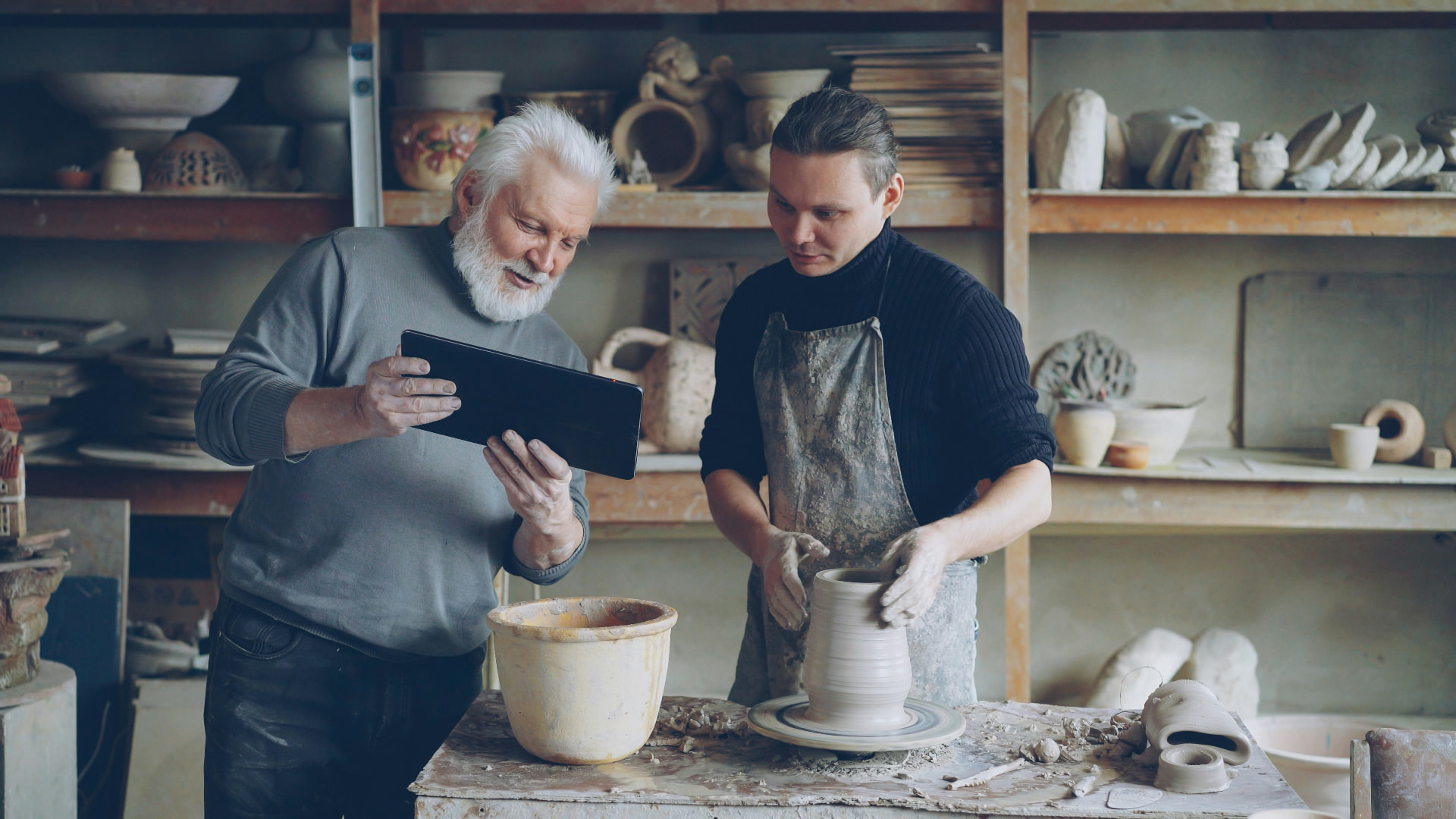 An experienced potter guiding another maker at the wheel
