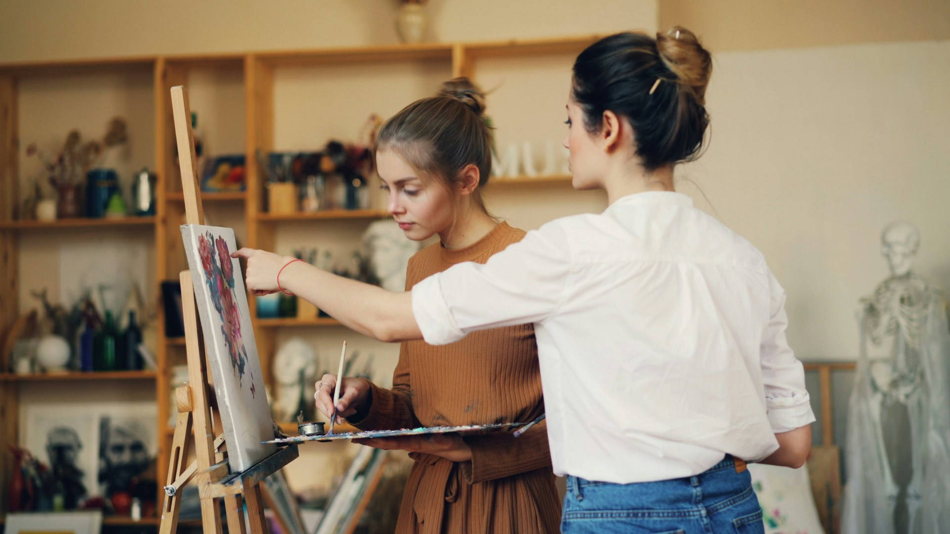 An instructor guiding a painter at an easel